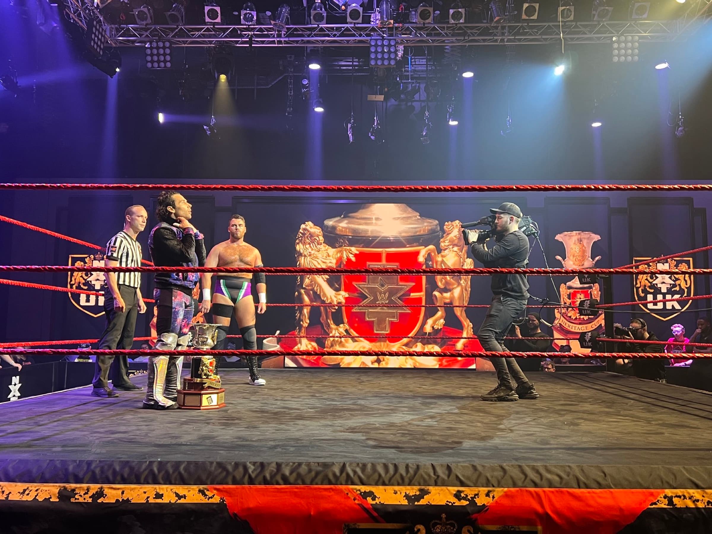 Steve McKinnon in the ring with a handheld broadcast camera at an NXT UK taping